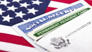 United States of America social security and green card with US flag on the background. Immigration concept. Closeup with shallow depth of field.